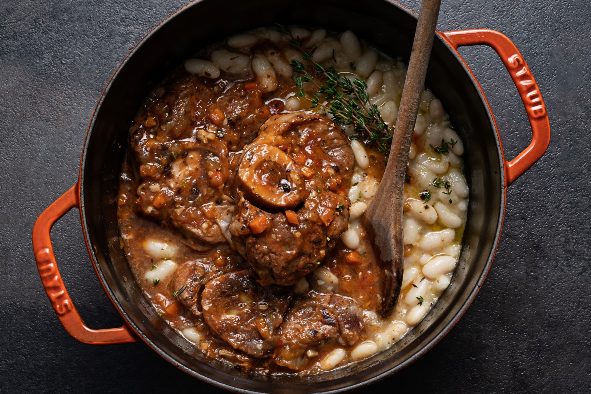 Veal Osso Buco in cooking pot with wooden spoon