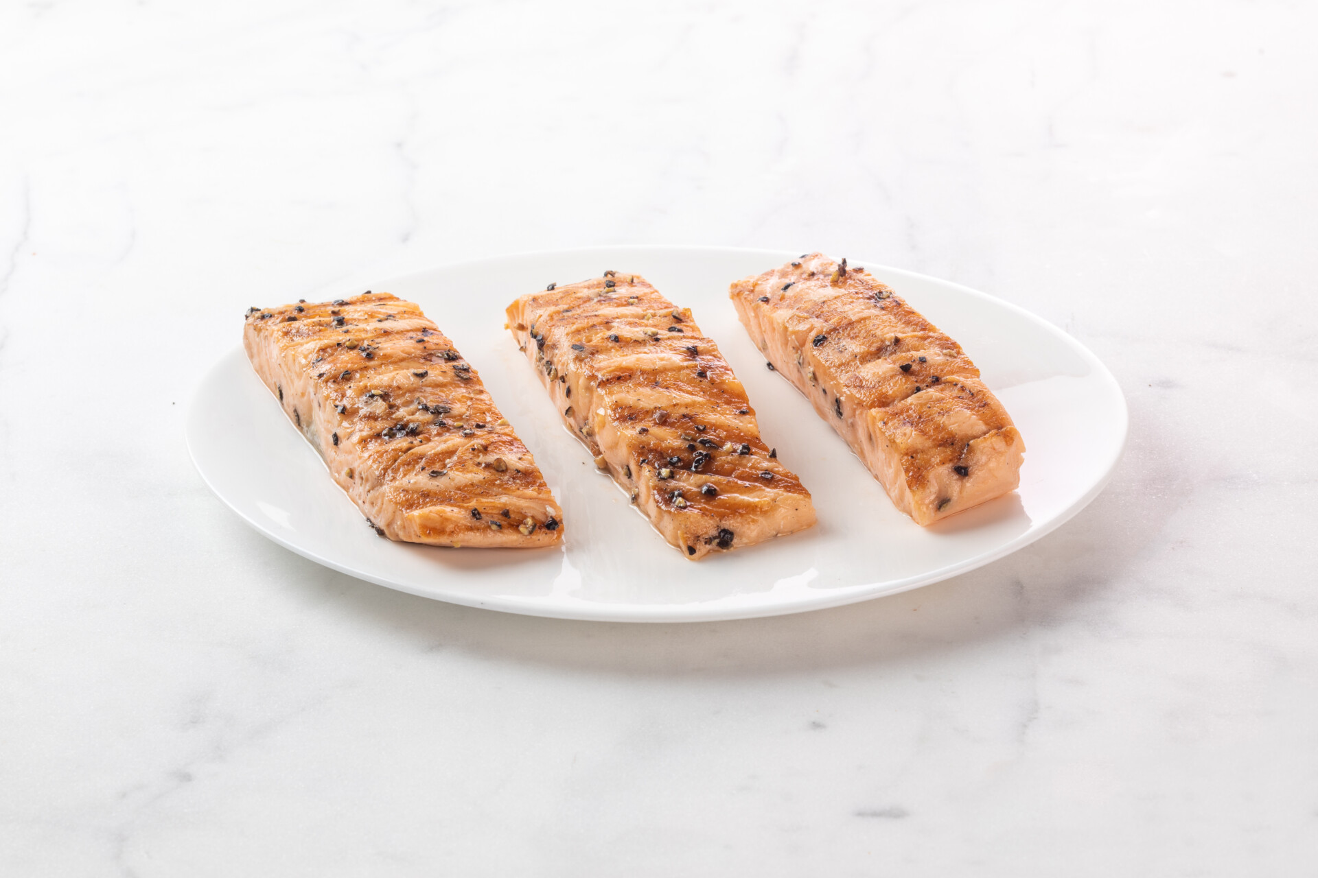 grilled salmon fillets on white plate