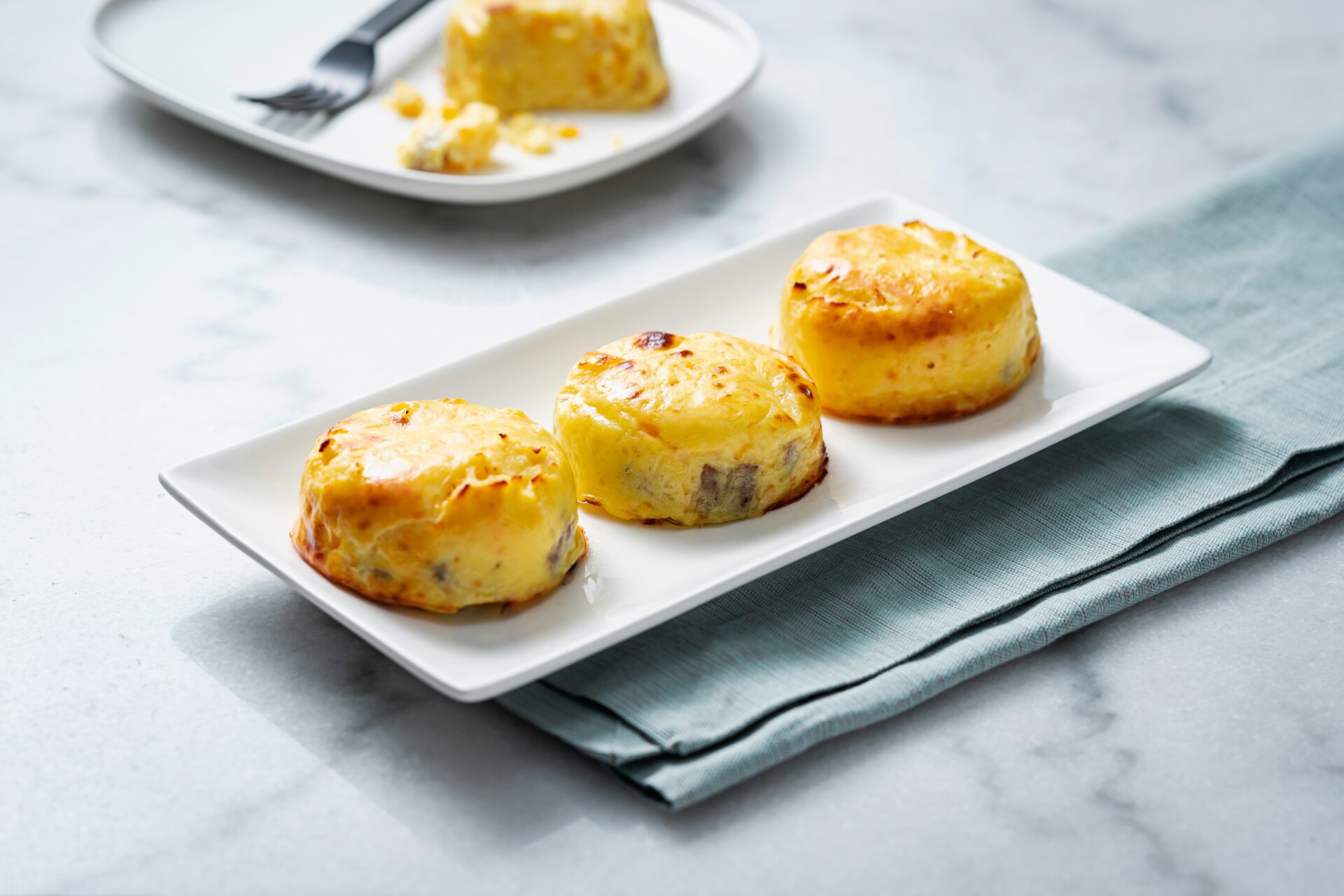 three egg bites on a white plate on marble counter